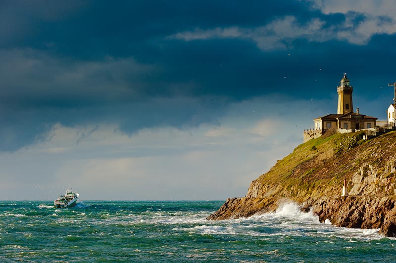 Faro San Juan de Nieva en loa alto señalando la ruta al barco saliendo de la ría de Avilés. Asturias. El color del mar Cantábrico es verde esmeralda y mar picada.