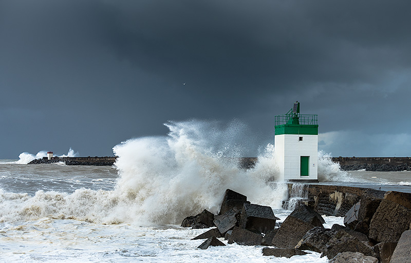 fotografia de la desembocadura del río Adour con altas olas golpeando el los muros de contención y contra las balizas roja de babor, al fondo de la imagen y verde para estribor en primer plano.